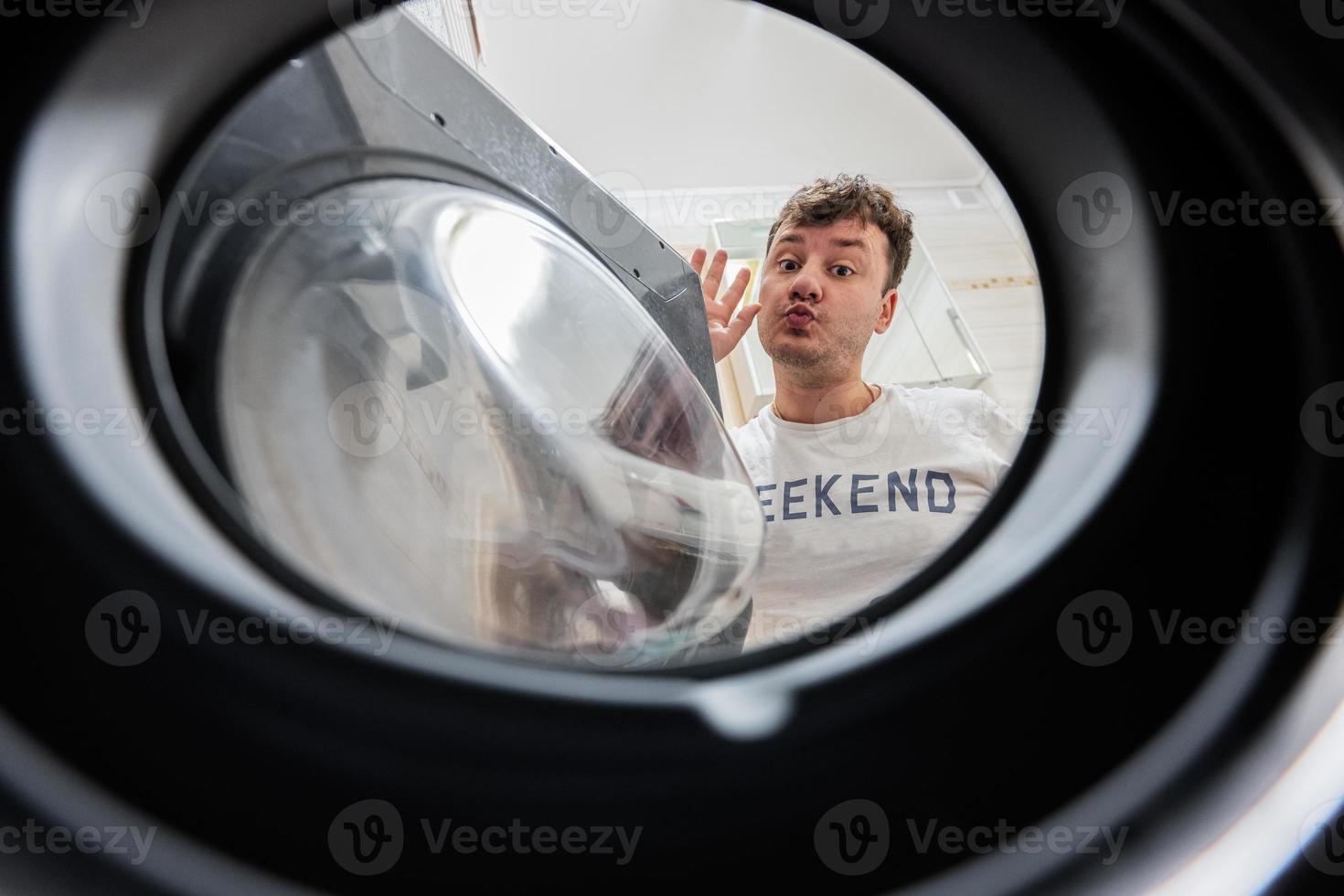 Man view from washing machine inside. Male does laundry daily routine. Kiss you. photo