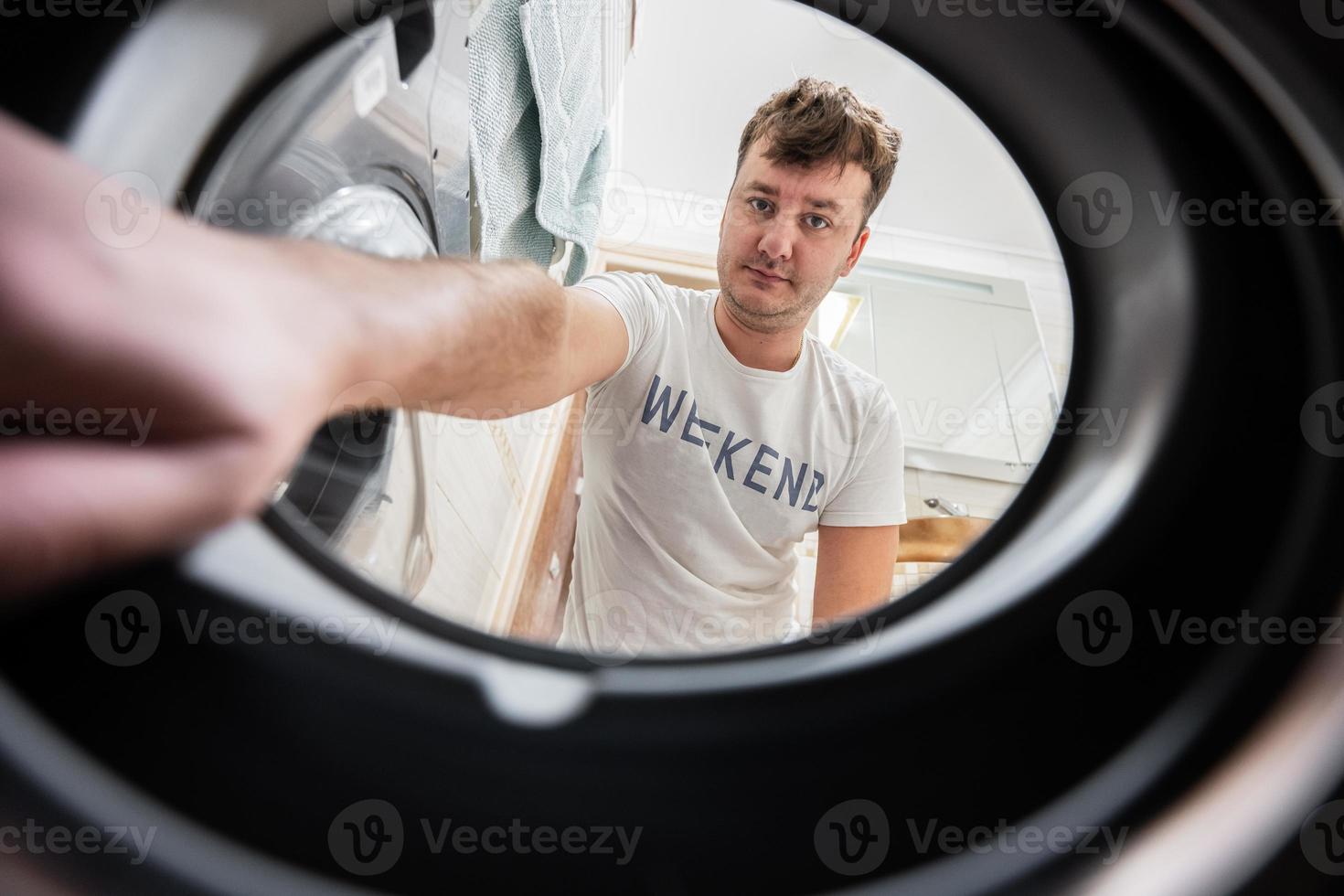 Man view from washing machine inside. Male does laundry daily routine. photo