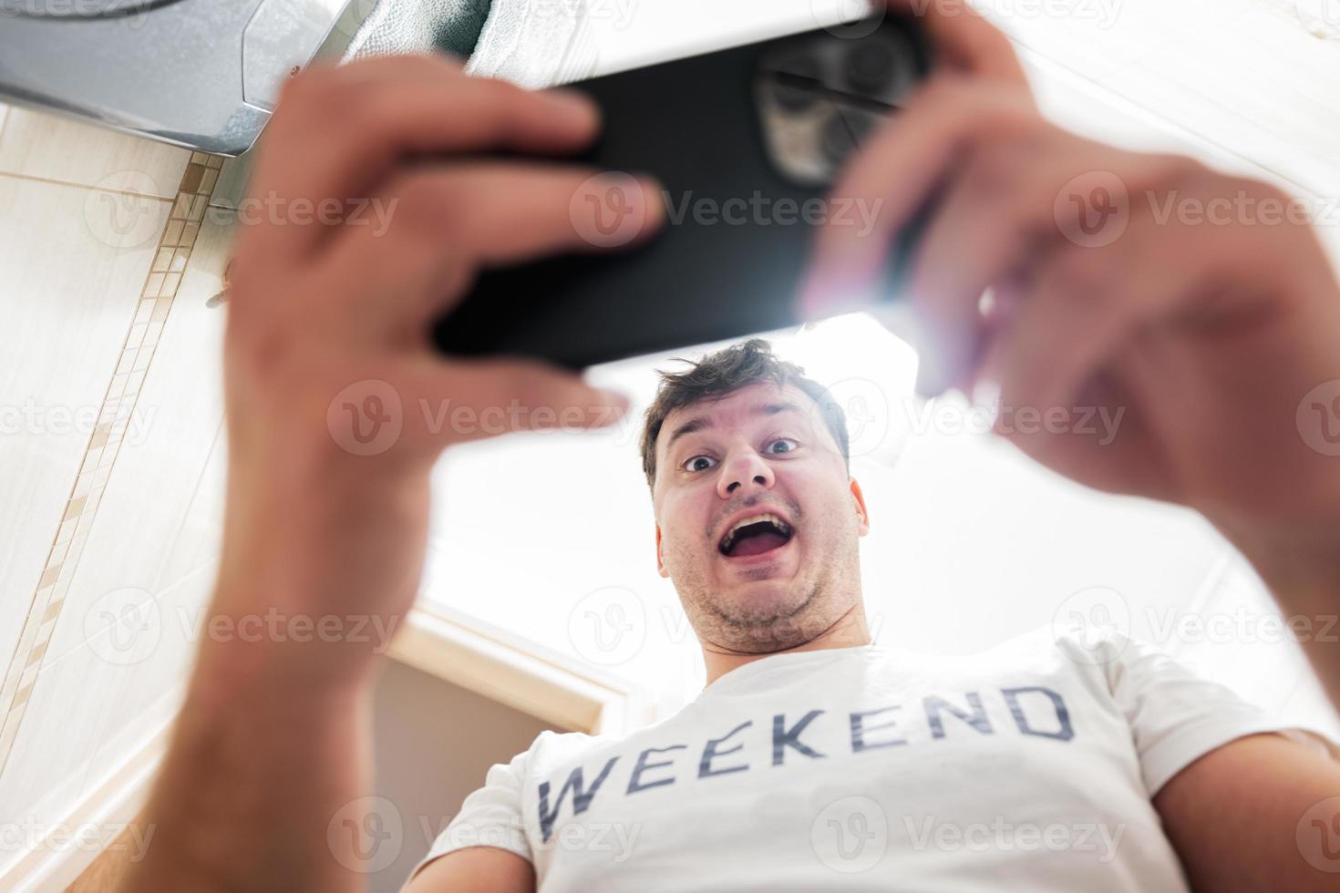 hombre con un sorprendido y contento cara mira a el teléfono pantalla. foto