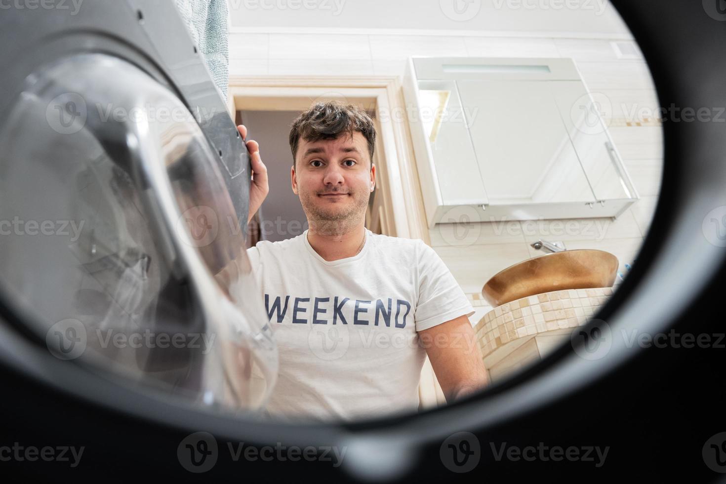 Man view from washing machine inside. Male does laundry daily routine. photo