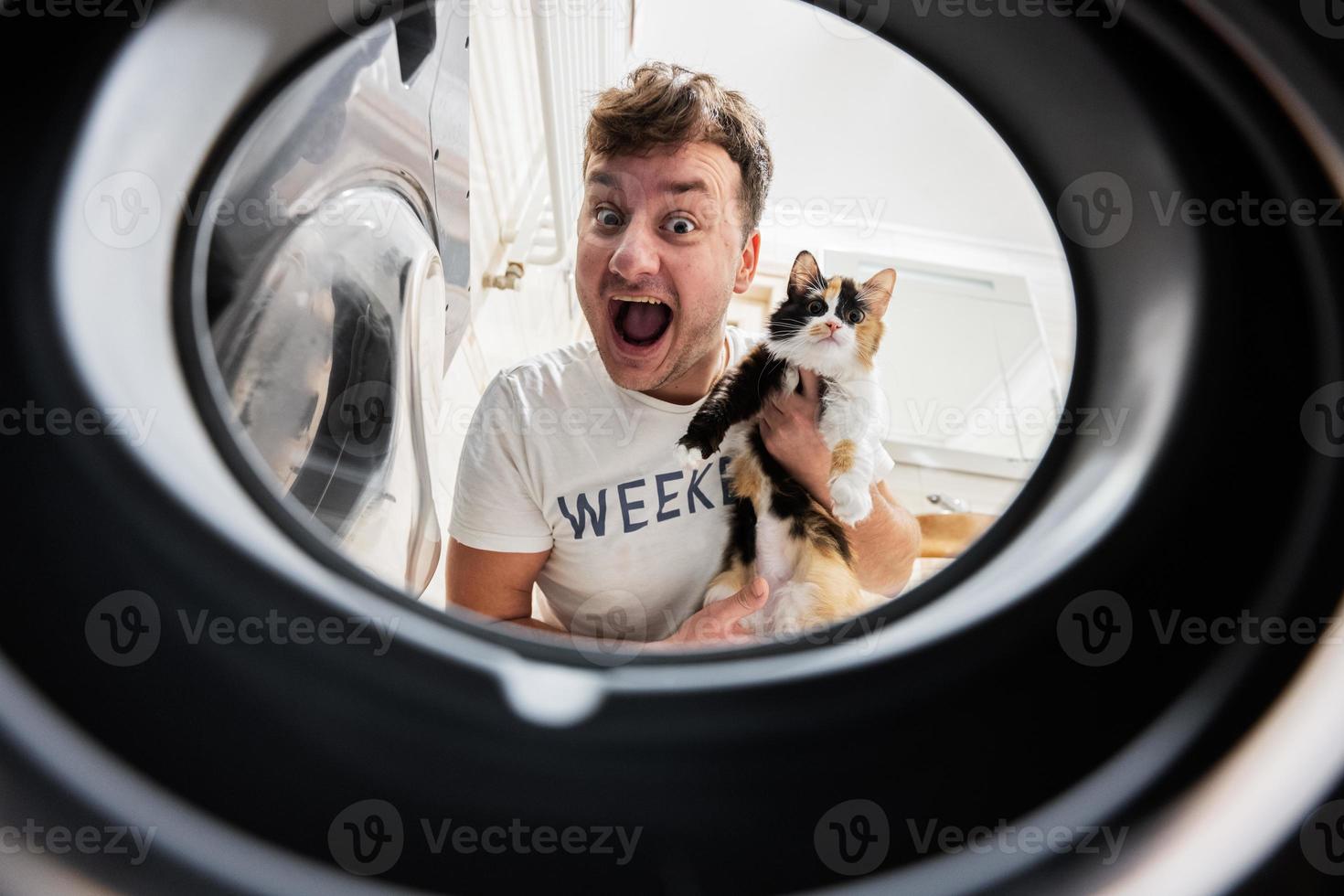 Man with cat view from washing machine inside. Male does laundry daily routine. photo