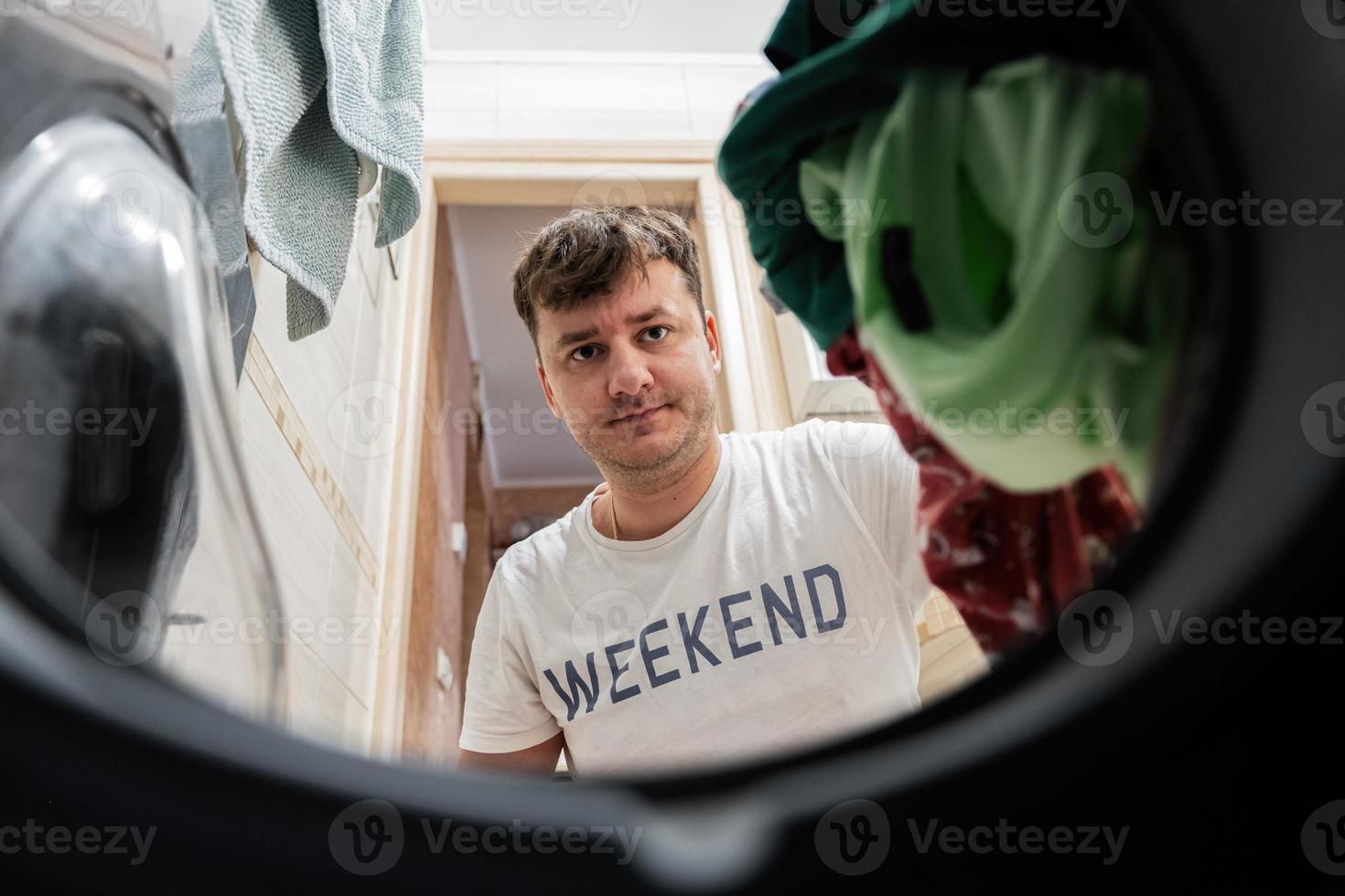 Man view from washing machine inside. Male does laundry daily routine. photo