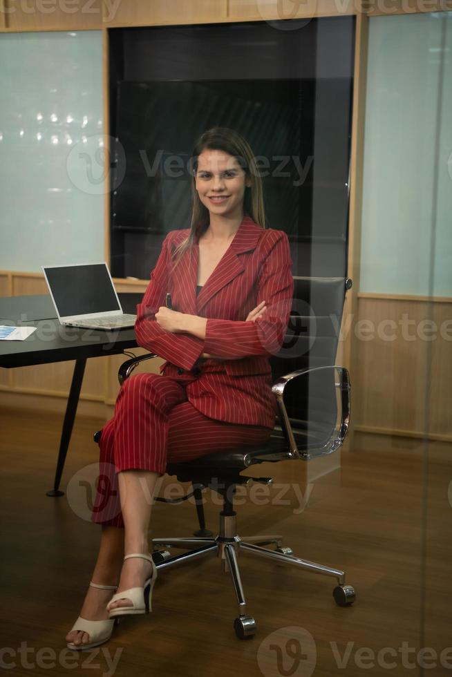 un mujer de negocios en un carmesí vestido preparar a presente trabajo y nuevo proyectos para consideración a el administración equipo. foto