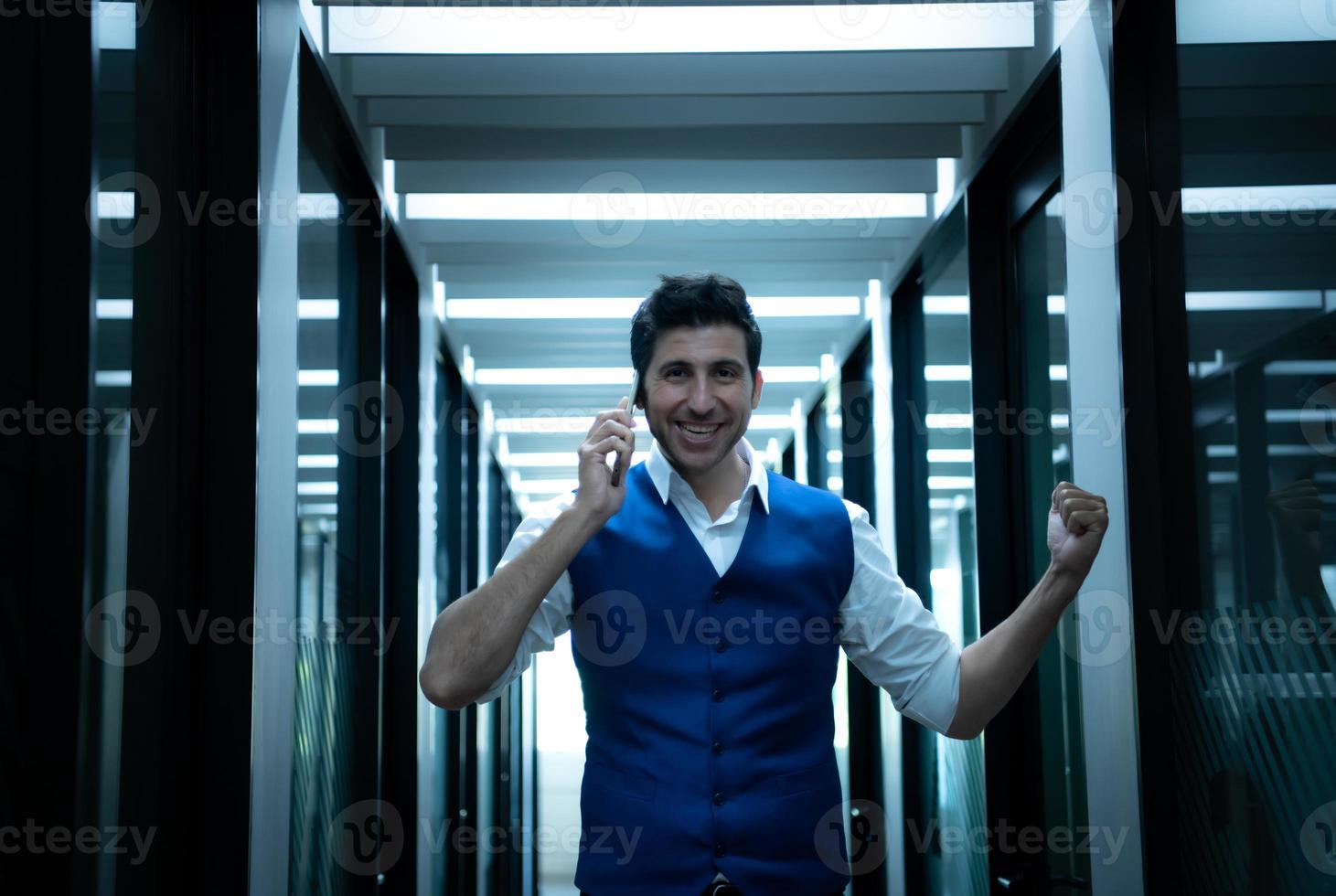 negocio hombre en el corredor de el conferencia habitación, hablando a un asistente en el teléfono a pedir para algunos detalles. foto