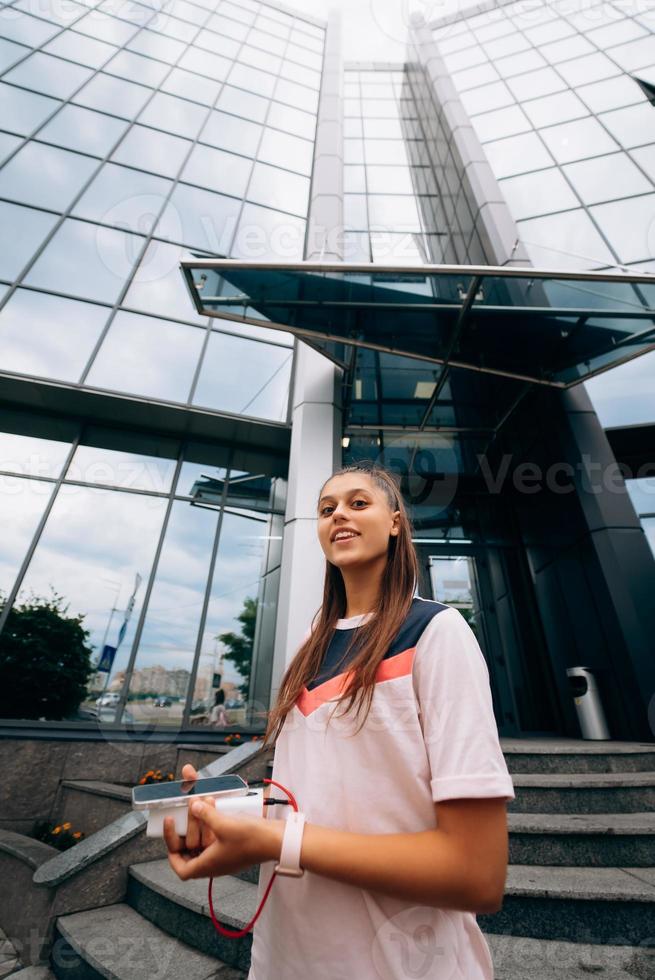 Sportswoman against modern building background outdoors walks in city photo
