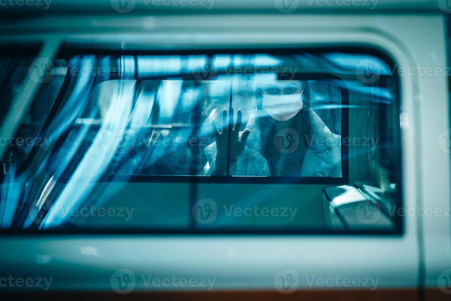 Brunette woman with mask looking out the window. photo