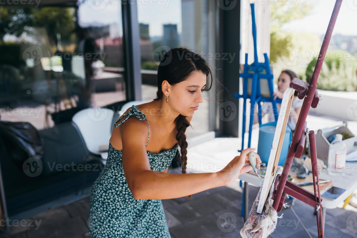 Young woman artist paints with a spatula on the canvas photo