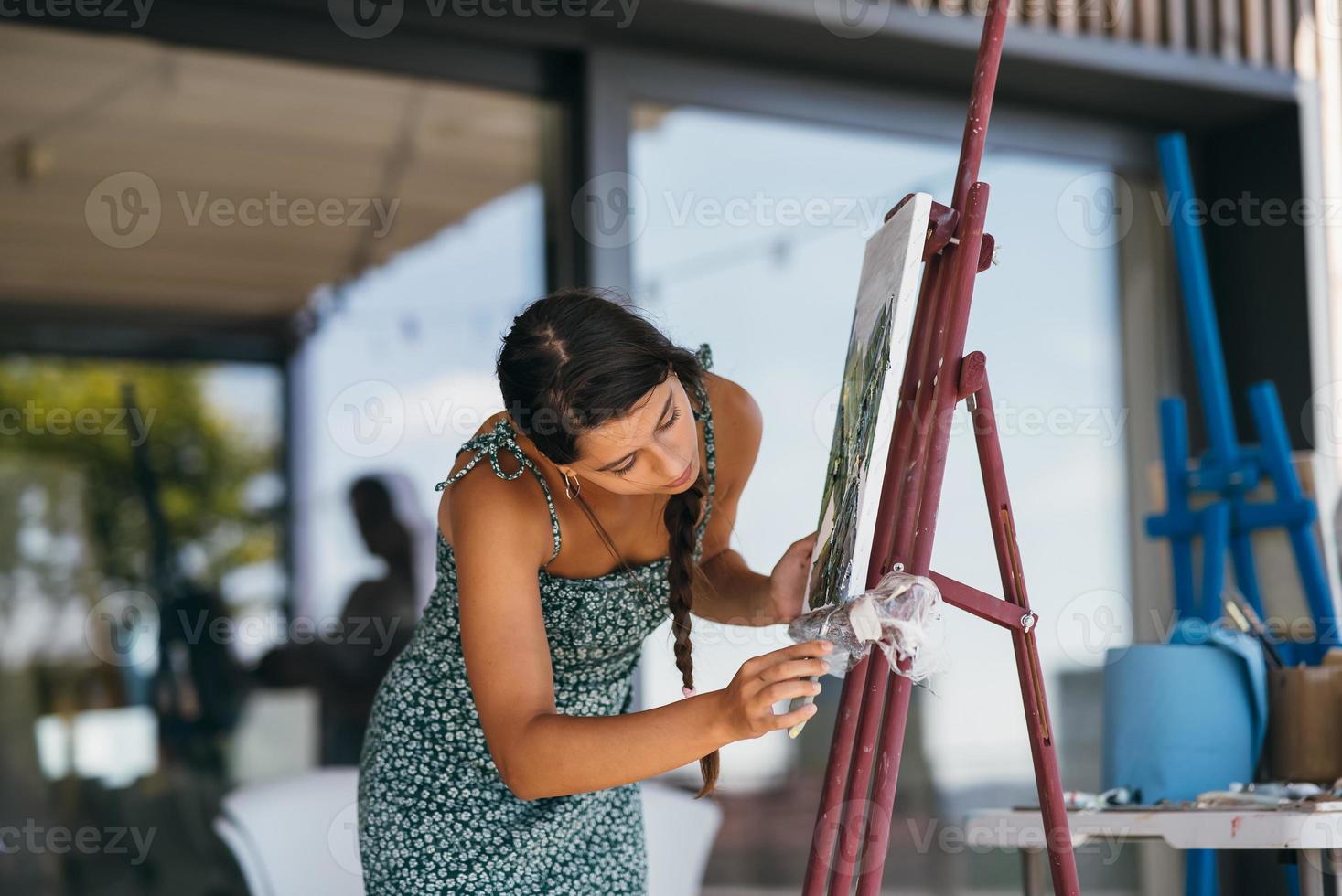 Young woman artist paints with a spatula on the canvas photo