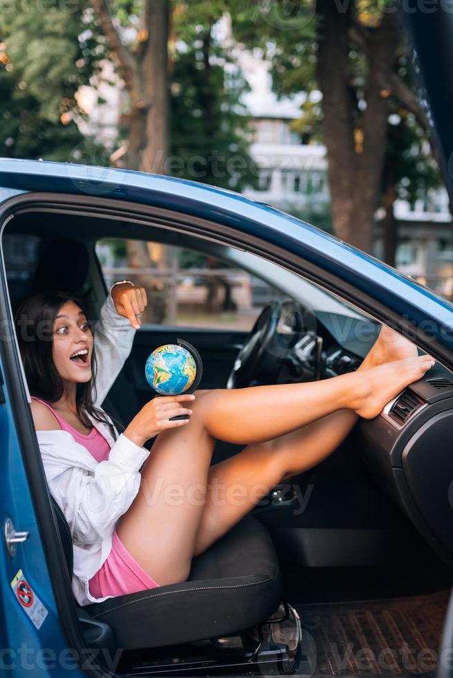 Young woman sitting in a car and holding a globe photo