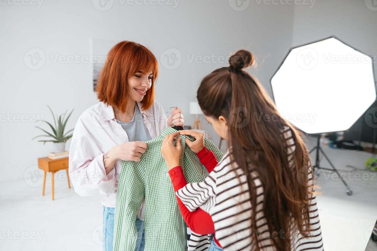 Happy beautiful young woman choosing clothes with girlfriend. photo