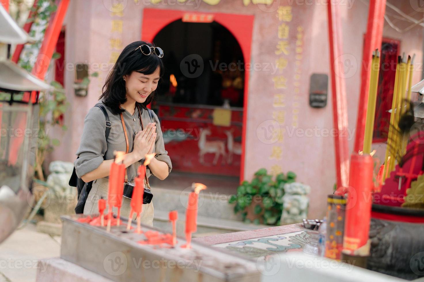 Portrait of asian woman saying prayers and eyes close in front of local Chinese shrine in Bangkok, Thailand photo