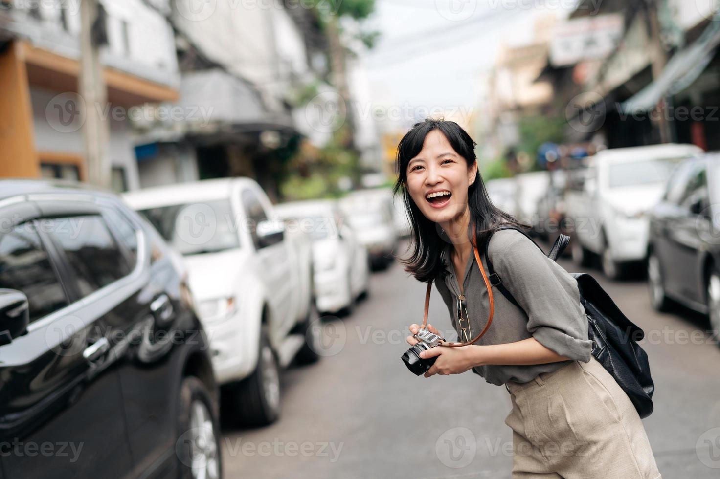 Young Asian woman backpack traveler using digital compact camera, enjoying street cultural local place and smile. Traveler checking out side streets. photo
