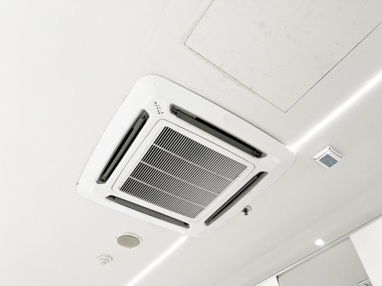 Ceiling mounted cassette type air conditioner and modern lamp light on white ceiling. duct air conditioner for home or office photo