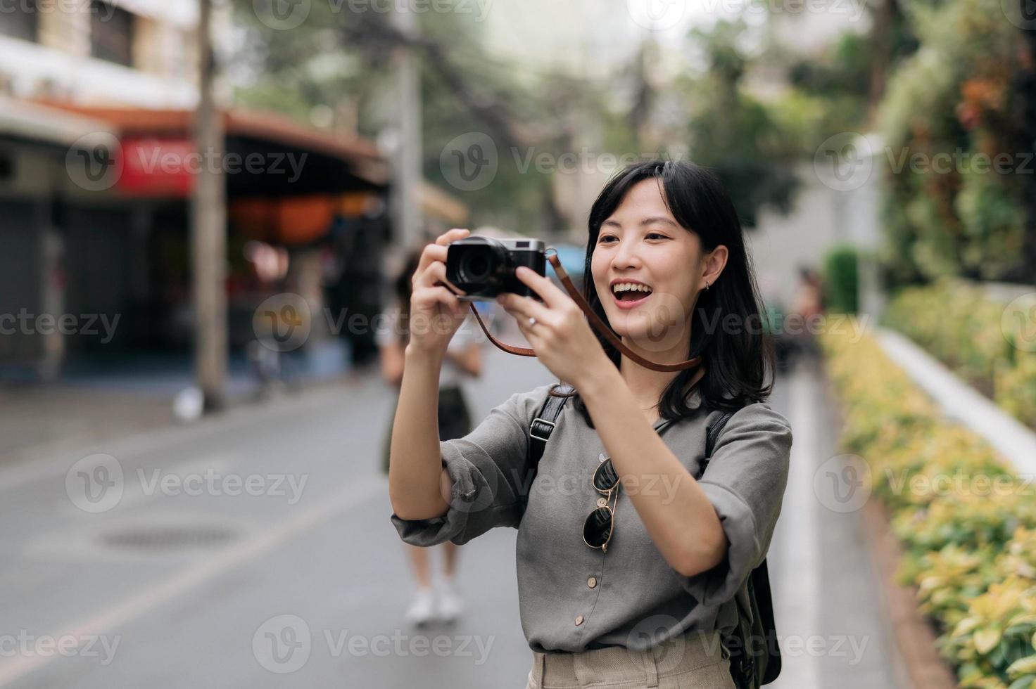 Young Asian woman backpack traveler using digital compact camera, enjoying street cultural local place and smile. Traveler checking out side streets. photo