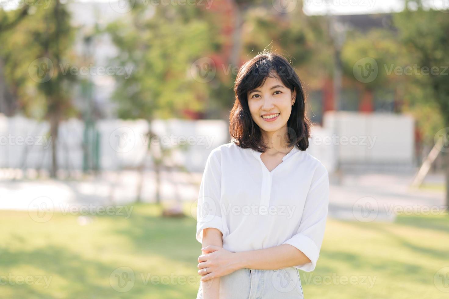 retrato joven hermosa asiático mujer con contento sonrisa alrededor al aire libre parque en soleado verano día foto