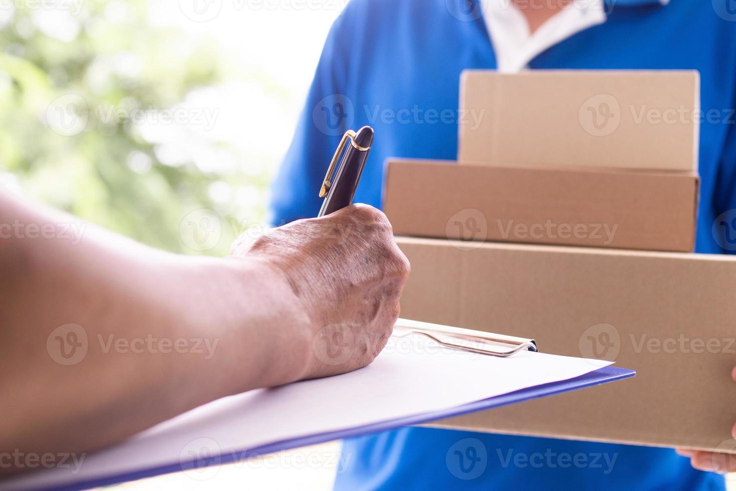 The landlord's hand is signing to receive the parcel sent by delivery man. photo