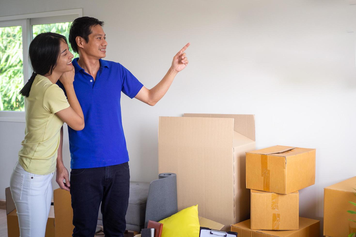 contento parejas en el nuevo hogar el esposa abrazado su marido, sonrió y disfruté mirando a el casa. Moviente casa y interior decorando ideas foto