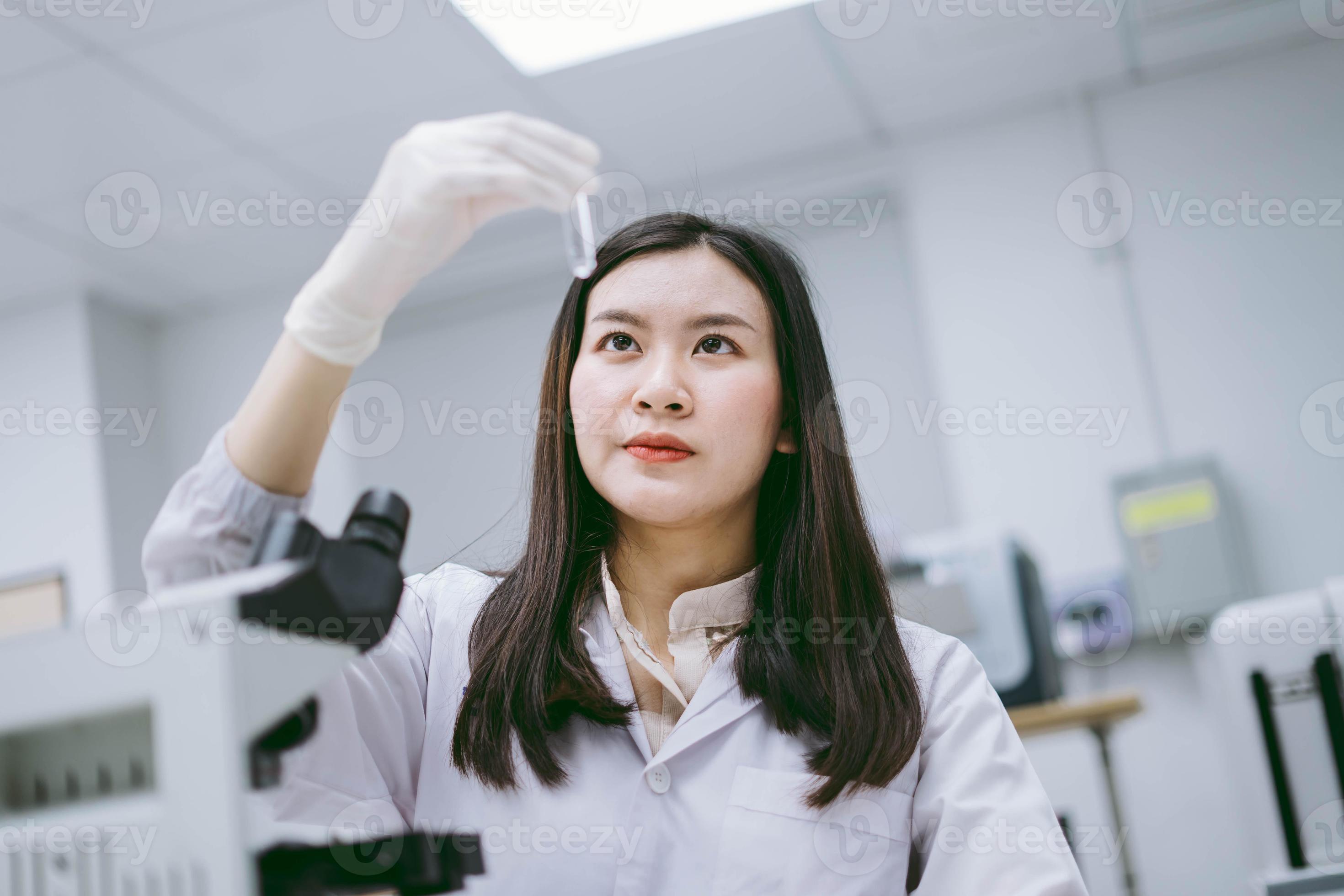 young female medical scientist looking at test tube in medical