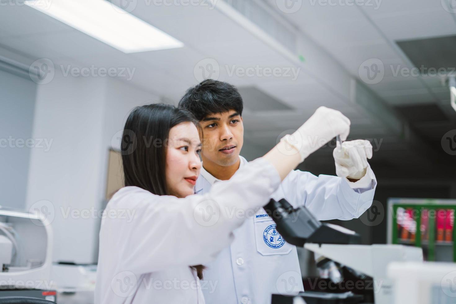 Two young medical scientist looking at test tube in medical laboratory , select focus on male scientist photo