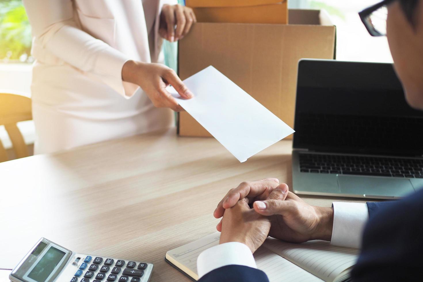 The business woman has a brown cardboard box next to her body and sends a letter of resignation to the executive. Include about resignation, job placement and vacancies. photo