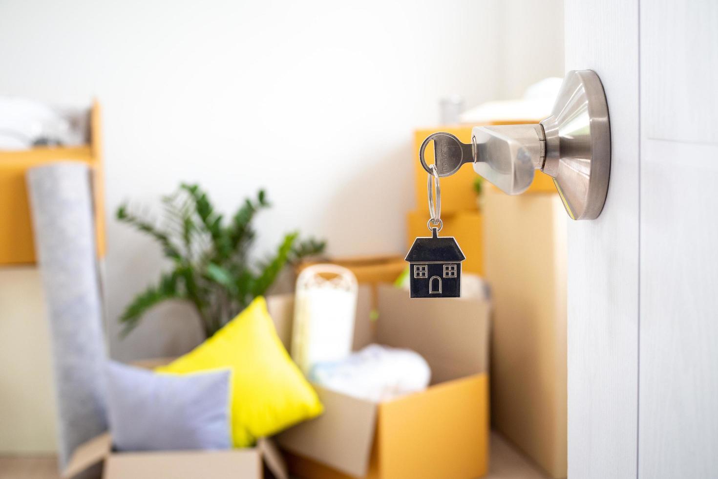 The key to the new house door that is open. With personal items after moving the house in the background. photo