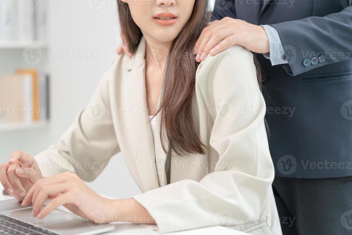 businessman sexually harassed a female colleague by touch her shoulder. Sexual harassment in office. Women feel anxious and stressed from being harassed. molest, assault, inappropriate, discrimination photo