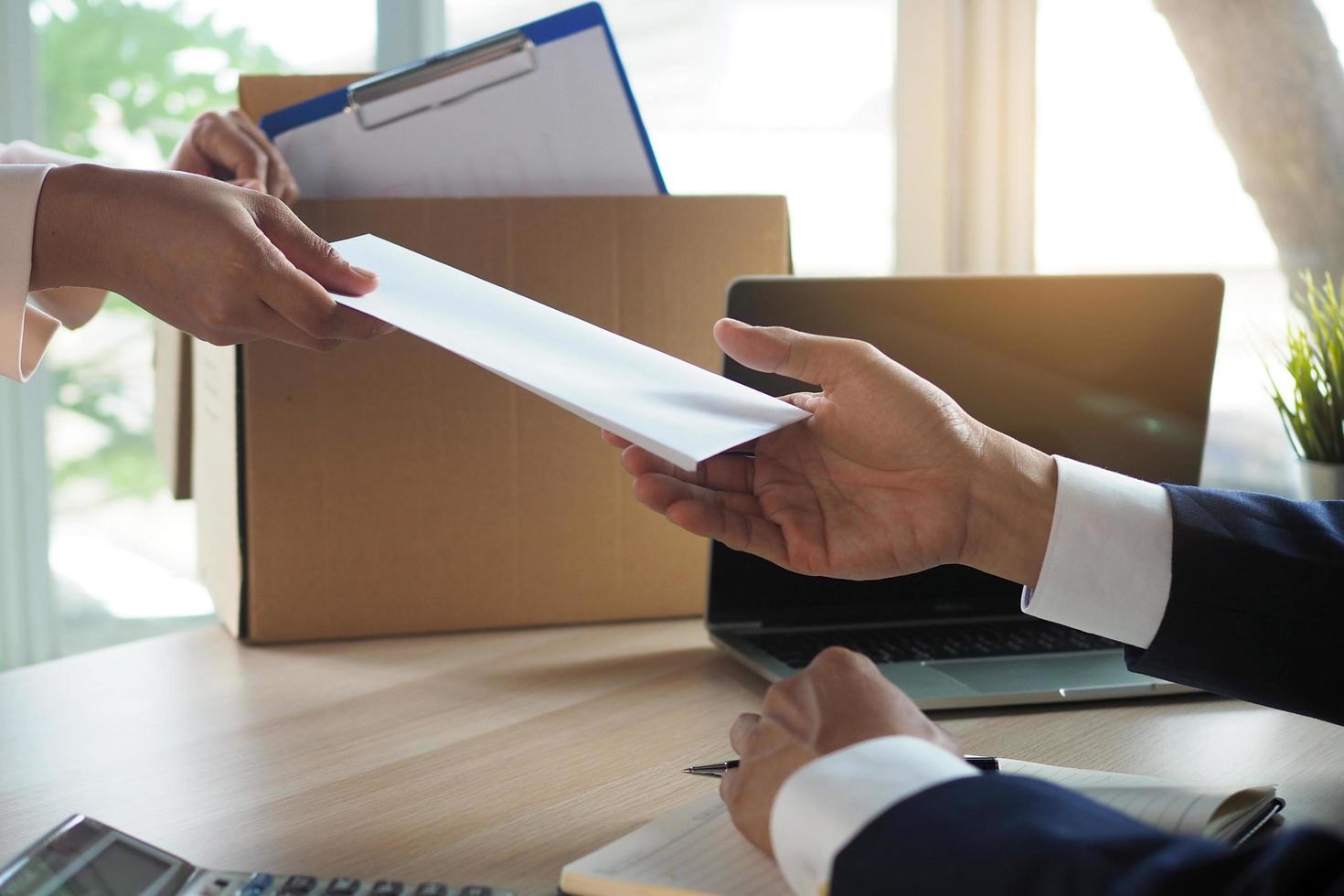 The business woman has a brown cardboard box next to her body and sends a letter of resignation to the executive. Include about resignation, job placement and vacancies. photo