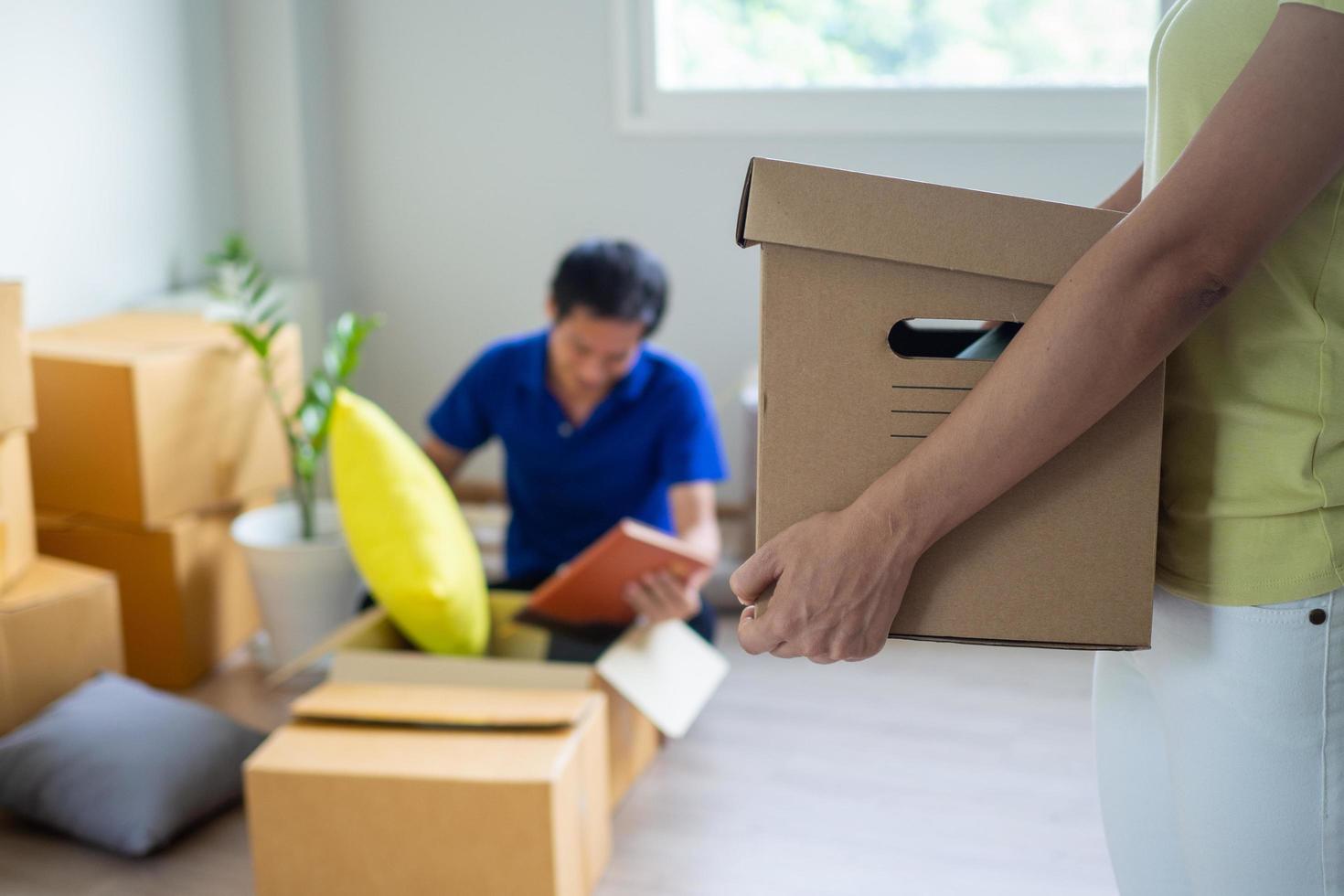 Wife carrying a box for personal belongings Prepare to move to a new home. Husband collecting personal items photo