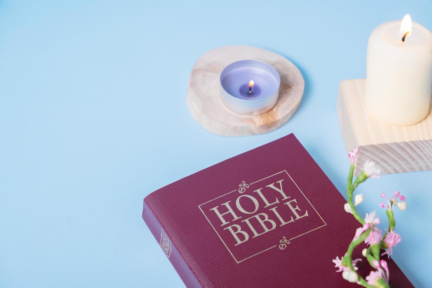 Christian Holy Bible with candles on blue background, flat lay, top view photo