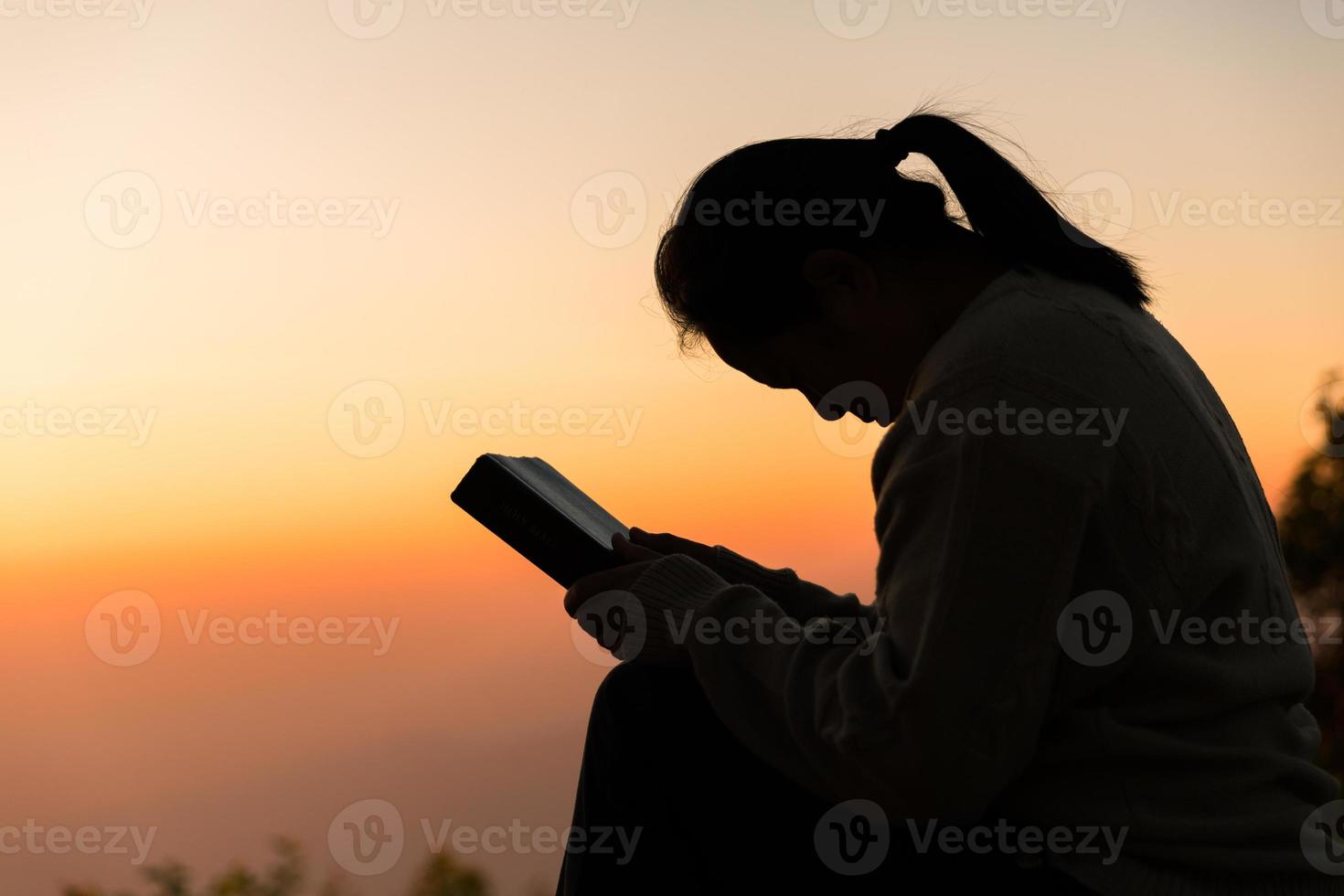 Silhouette of woman kneeling down praying for worship God at sky background. Christians pray to jesus christ for calmness. In morning people got to a quiet place and prayed. copy space. photo