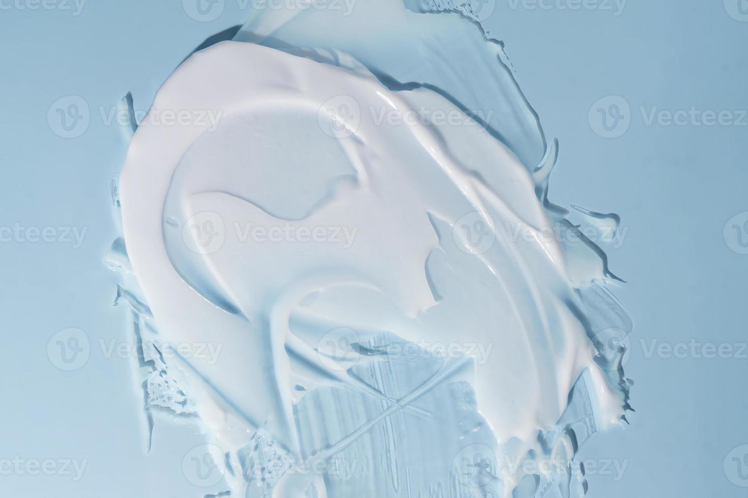 A smear of cosmetic cream i on a blue background. Skin care product smear. Lotion, hair mask or other csmetic product texture with copy space photo