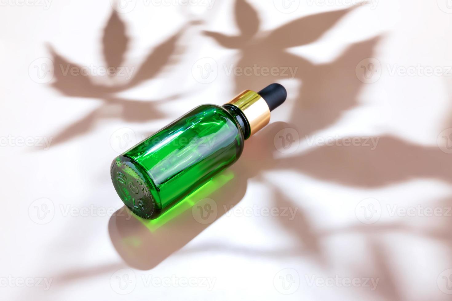 vaso botella de cbd o thc petróleo con cáñamo o médico canabis planta hojas en beige antecedentes con cáñamo hojas sombra y Copiar espacio foto