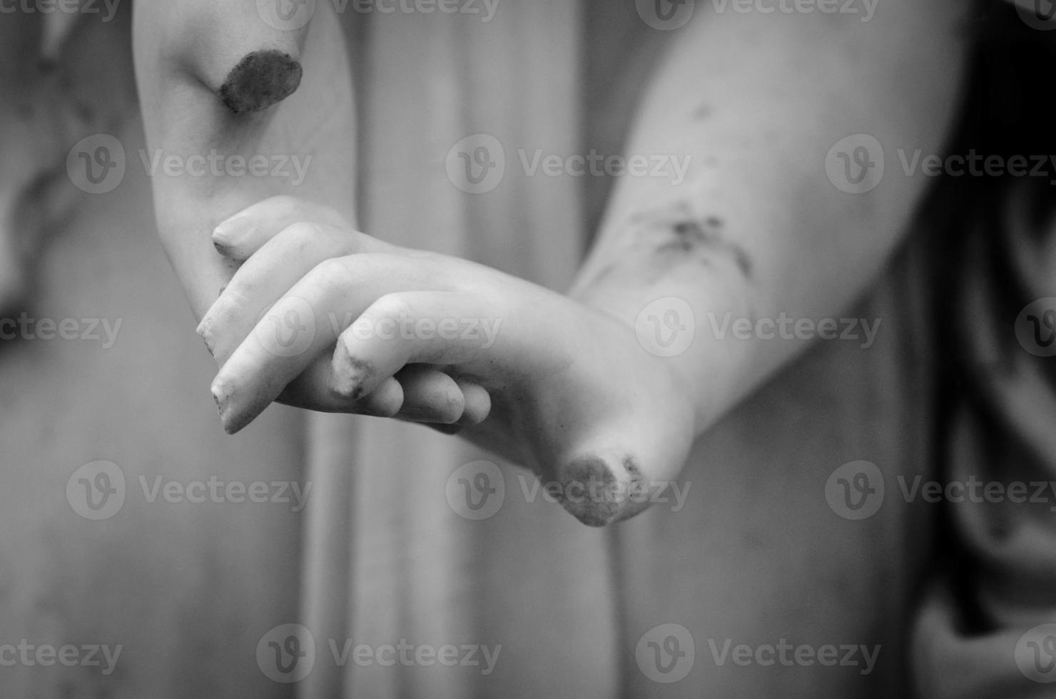 Black and white photograph of old broken statues holding hands photo