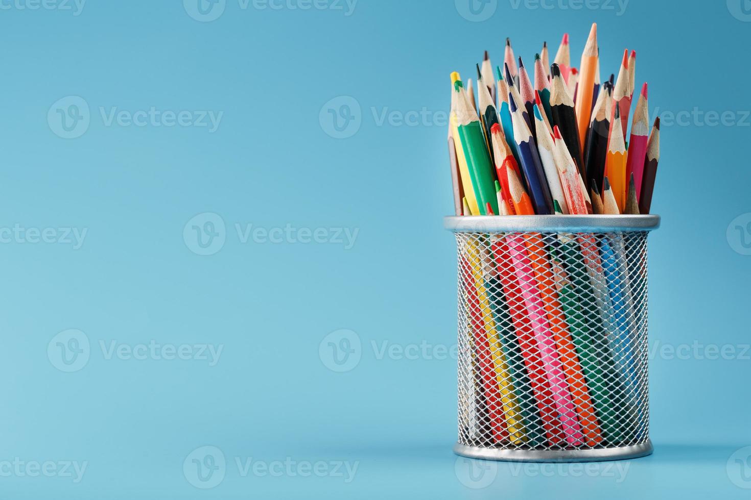 Colorful pencils in a metal jar on a blue background. photo