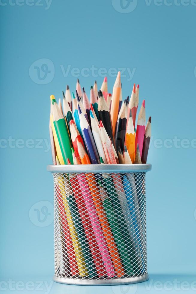 Colorful pencils in a metal jar on a blue background. photo