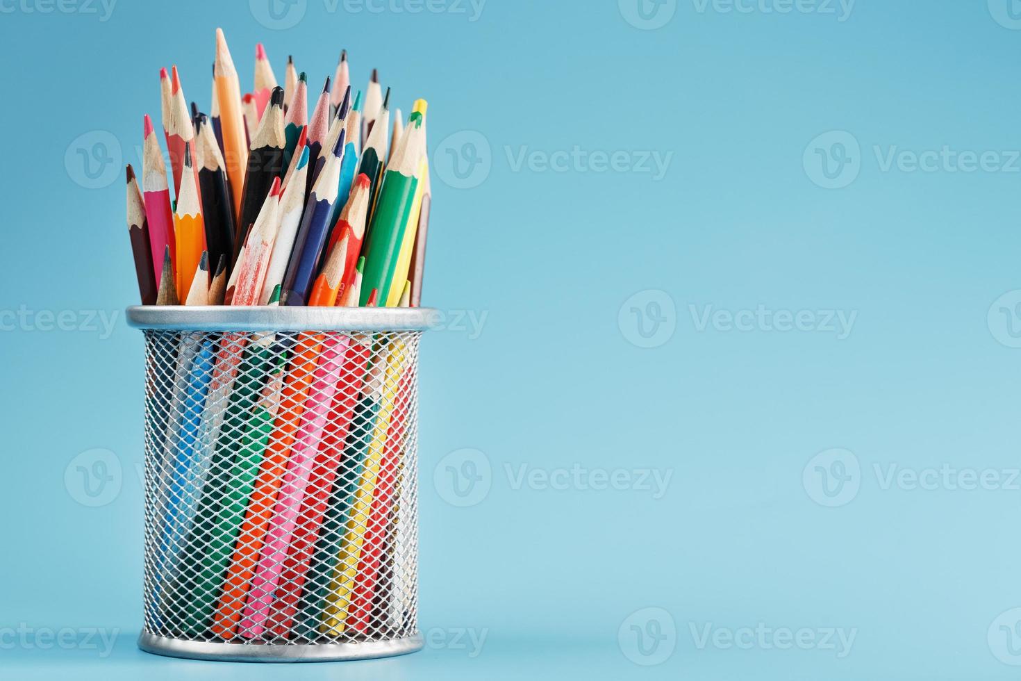 Colorful pencils in a metal jar on a blue background. photo