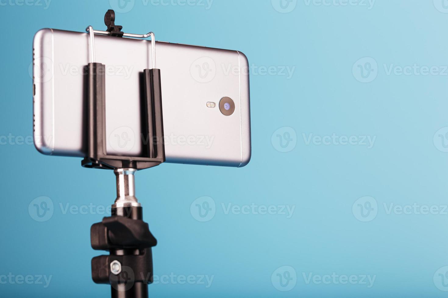 Smartphone on a tripod as a photo-video camera on a blue background. Record videos and photos for your blog.