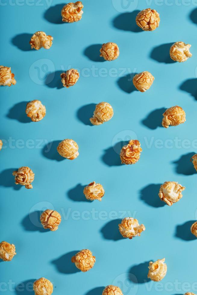 Patterns of caramel popcorn on a blue background in the form of a pattern. photo