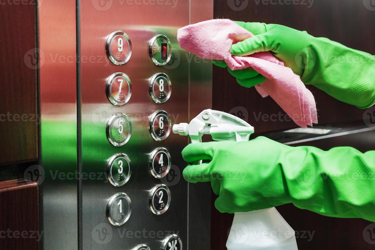 desinfección y cuidado higiénico con spray de alcohol en el botón del ascensor. foto