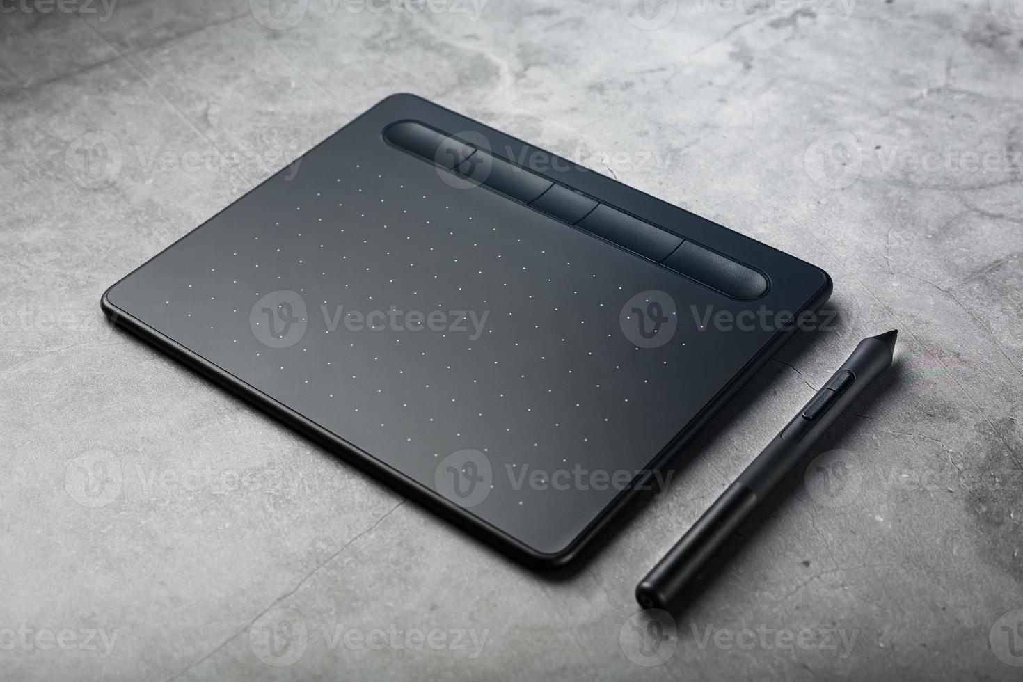 Graphic tablet with a stylus on a dark textural background, top view. Gadget for working as a designer, artist and photographer photo