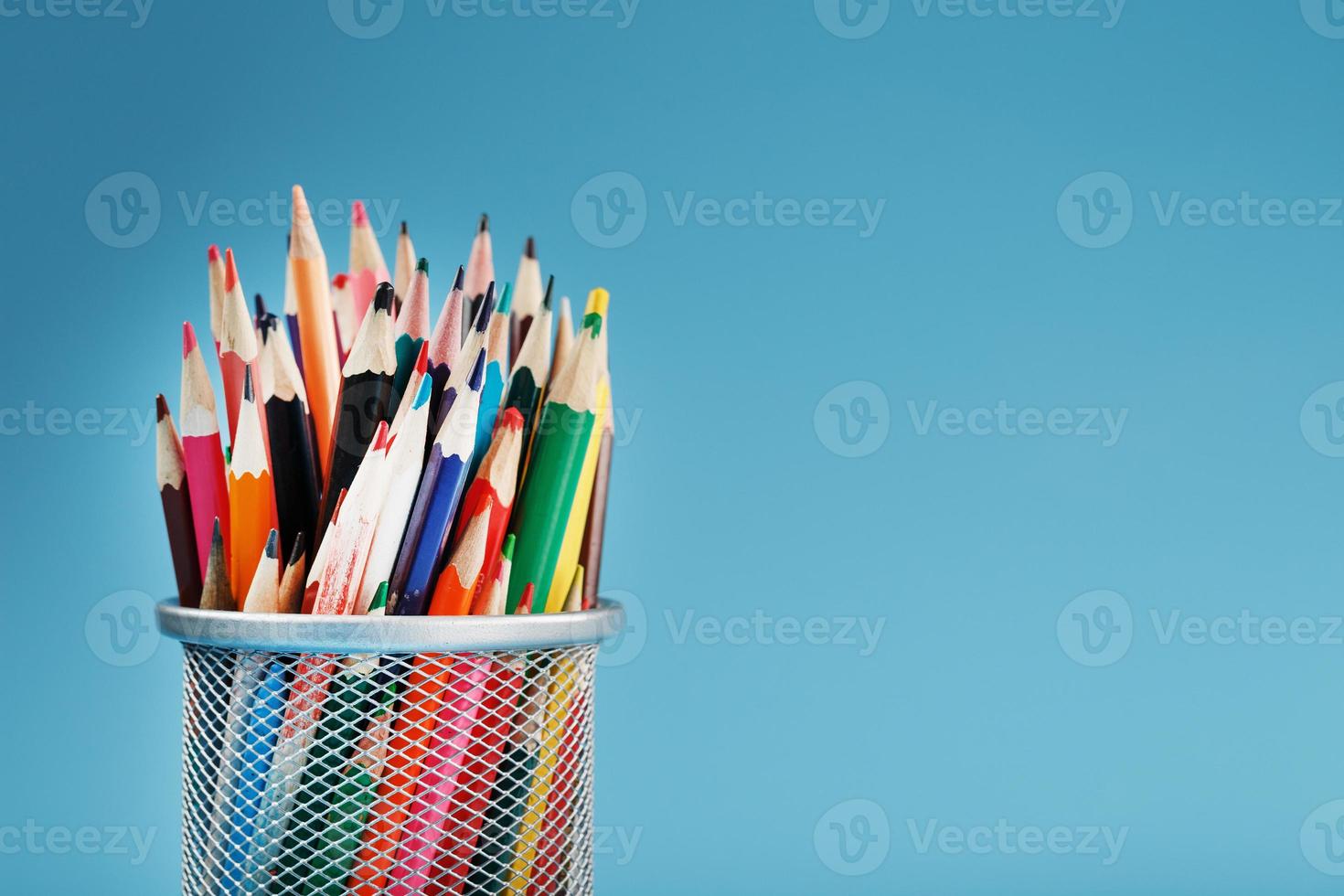 Colorful pencils in a metal jar on a blue background. photo