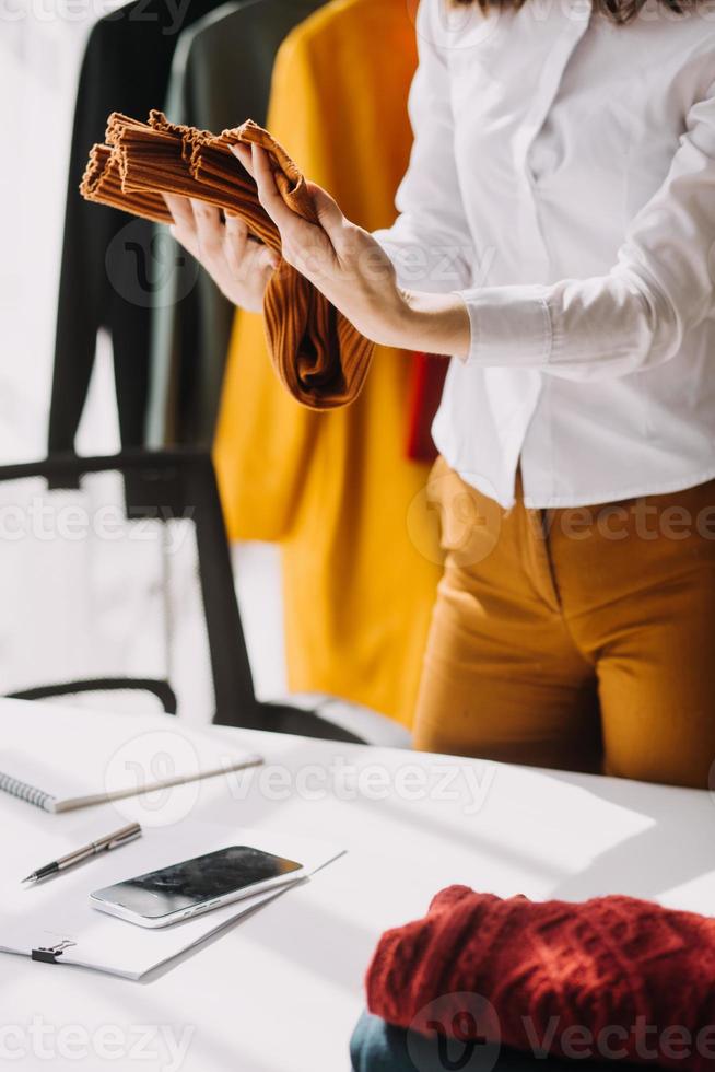 Beautiful lady blogger showing clothes in front of the camera to recording vlog video live streaming at her shop. Online Shopping Cart notion. photo