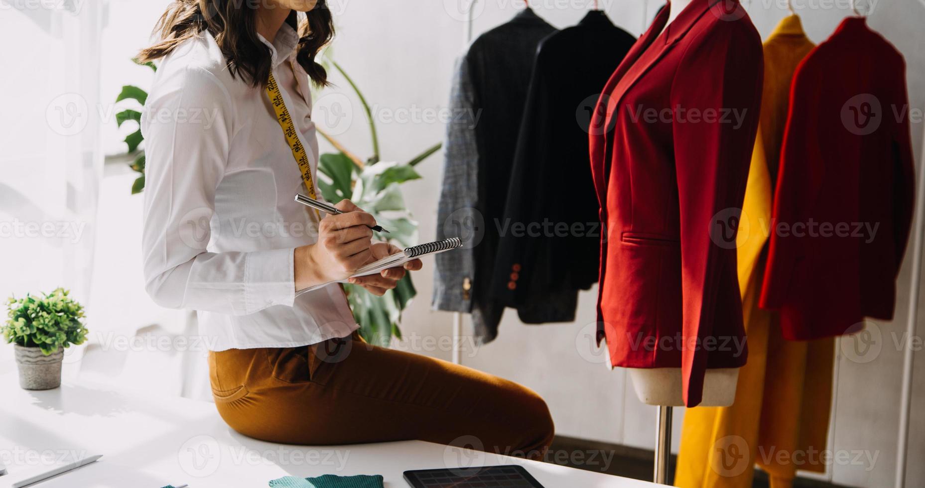 Beautiful lady blogger showing clothes in front of the camera to recording vlog video live streaming at her shop. Online Shopping Cart notion. photo