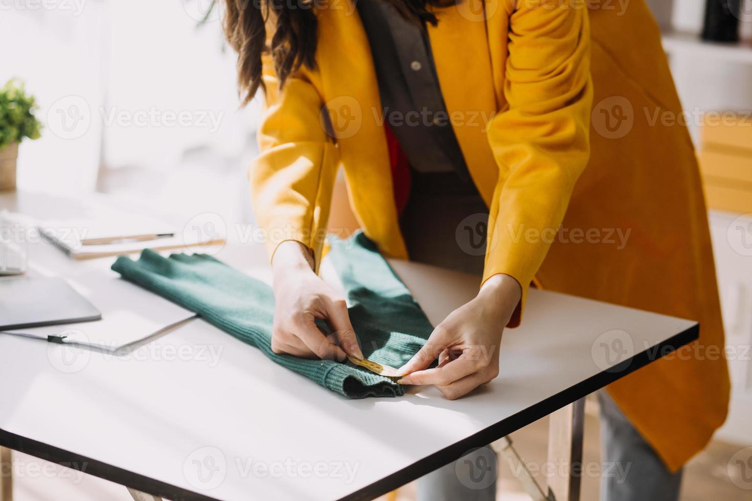 Beautiful lady blogger showing clothes in front of the camera to recording vlog video live streaming at her shop. Online Shopping Cart notion. photo