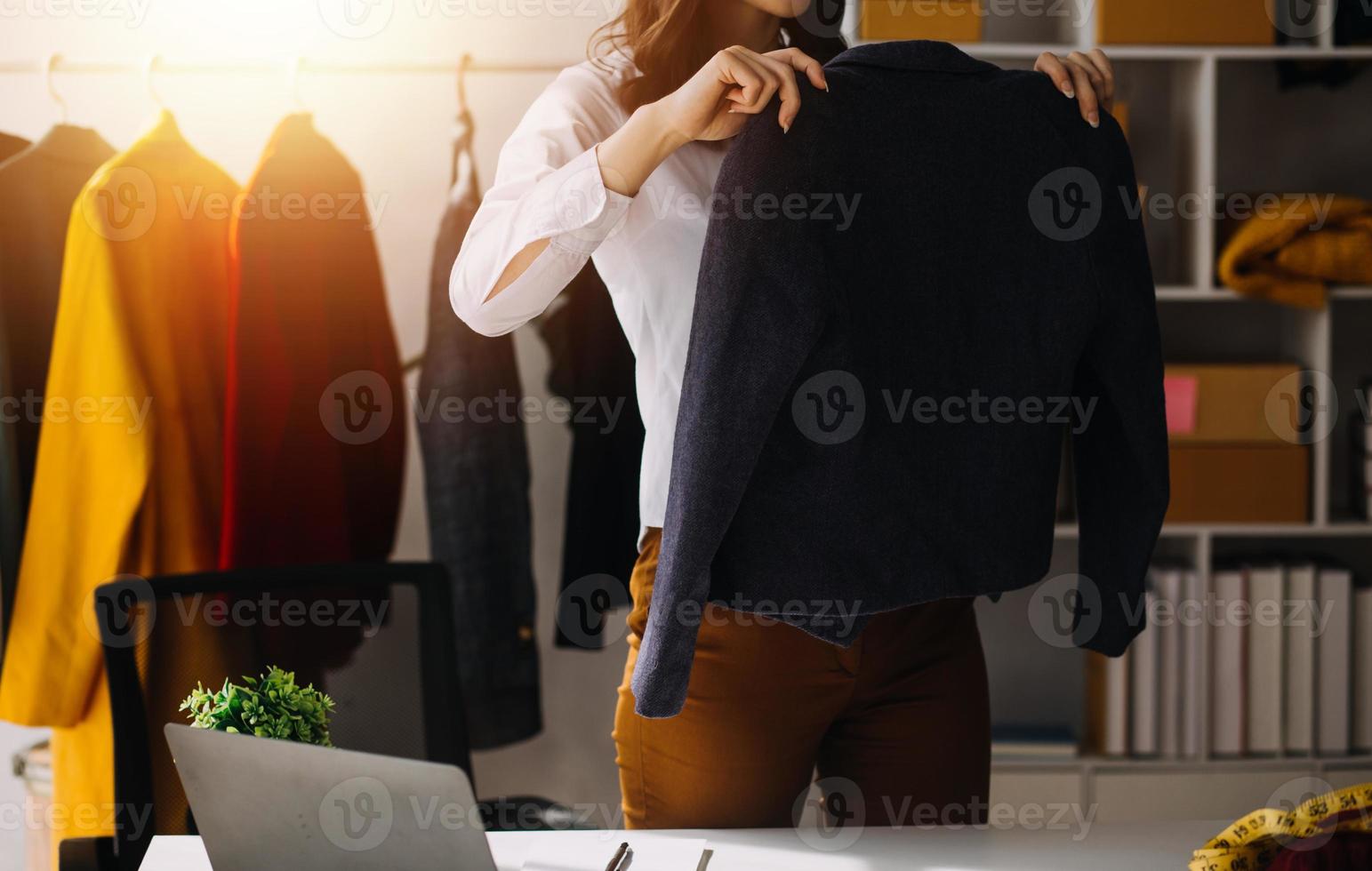 Beautiful lady blogger showing clothes in front of the camera to recording vlog video live streaming at her shop. Online Shopping Cart notion. photo