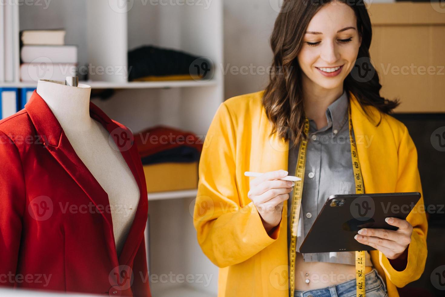 Beautiful lady blogger showing clothes in front of the camera to recording vlog video live streaming at her shop. Online Shopping Cart notion. photo