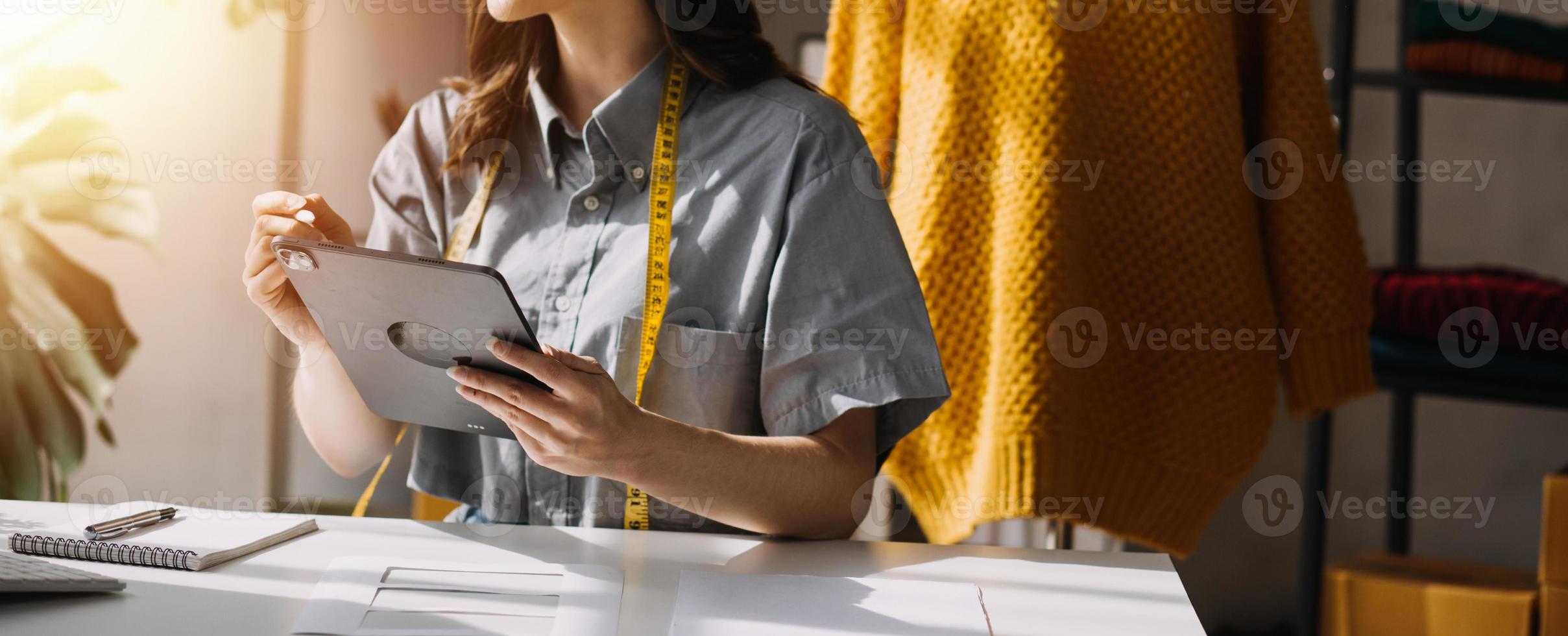 Beautiful lady blogger showing clothes in front of the camera to recording vlog video live streaming at her shop. Online Shopping Cart notion. photo
