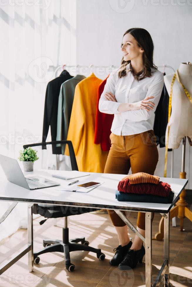 Beautiful lady blogger showing clothes in front of the camera to recording vlog video live streaming at her shop. Online Shopping Cart notion. photo