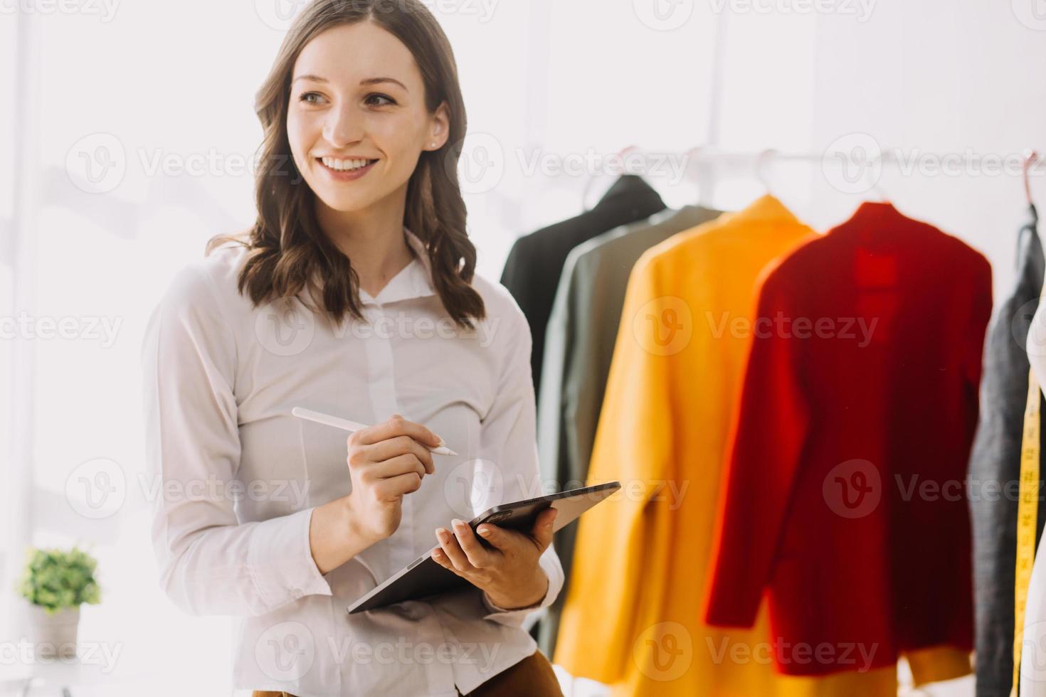 Beautiful lady blogger showing clothes in front of the camera to recording vlog video live streaming at her shop. Online Shopping Cart notion. photo