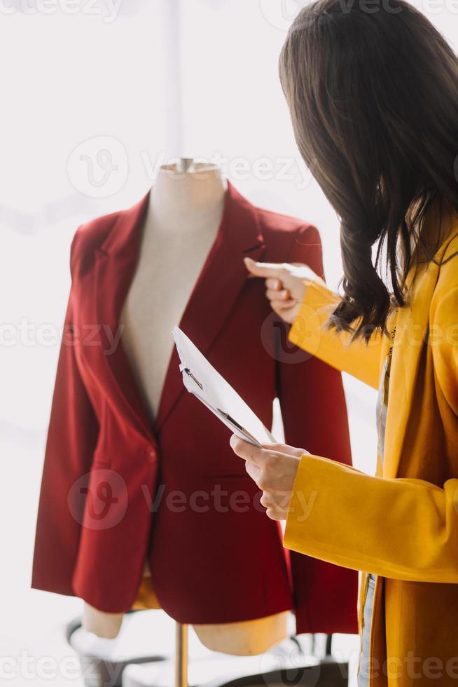 Beautiful lady blogger showing clothes in front of the camera to recording vlog video live streaming at her shop. Online Shopping Cart notion. photo